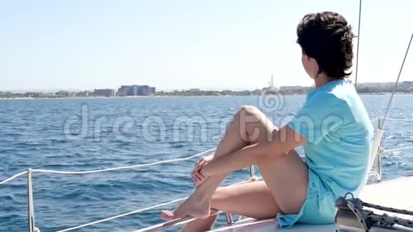 这个女孩正在公海上阳光明媚的一天在游艇或船上休息一个女人坐在甲板上看着视频的预览图
