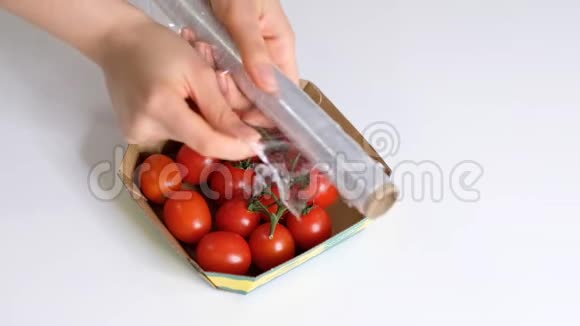 女人用食物胶片在白色桌子上储存食物包装产品用透明聚乙烯食品膜辊视频的预览图