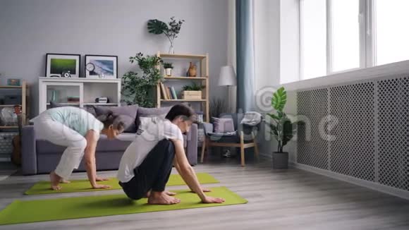 快乐的一对夫妇一起做瑜伽平衡手臂在家锻炼视频的预览图