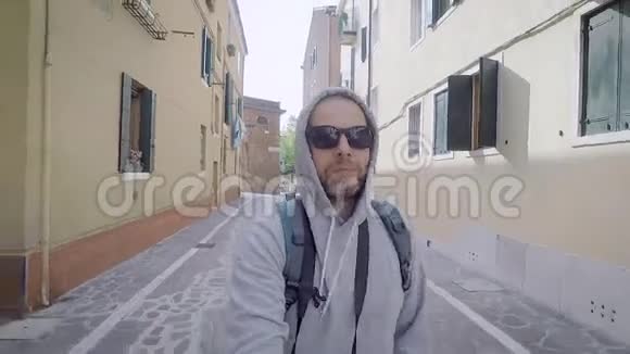 一个快乐的农民游客穿过一个欧洲城市一个男人对着自拍相机微笑智能手机视频的预览图