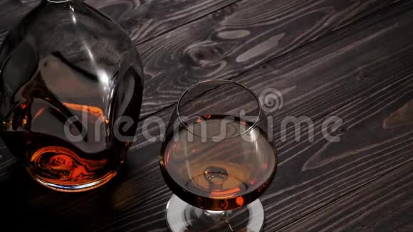 豪华白兰地手把两个玻璃杯中的一个从右边放在木桌上白兰地白兰地嗅探器狂欢慢动作视频的预览图