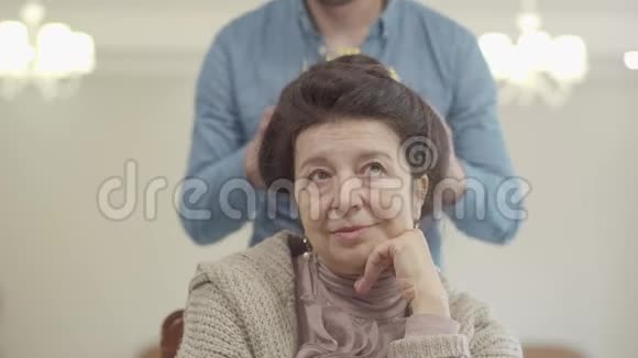 可爱的成熟女人的肖像成年孙子带着王冠戴在老太太的头上视频的预览图
