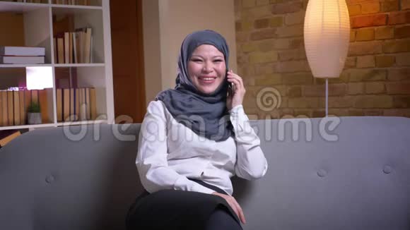穆斯林成年女性戴头巾的特写镜头在手机上交谈坐着开心地微笑视频的预览图