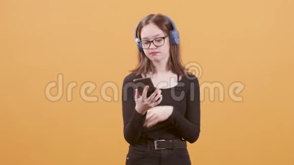 少女在智能手机上唱一首歌在耳机里倾听视频的预览图