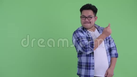 快乐的年轻超重的亚洲潮人拍手指展示一些东西视频的预览图