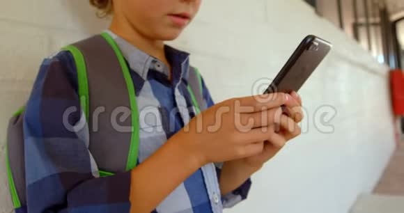 在学校走廊4k斜靠在墙上时使用手机的白人学童的侧视图视频的预览图