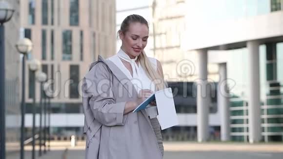 年轻的商务女性写在笔记本上站在市中心视频的预览图