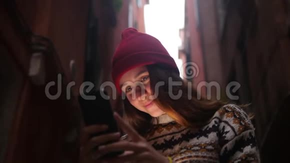 一个年轻微笑的女人站在街上看着手机屏幕一道光照亮了她的脸视频的预览图