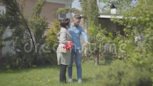 成熟的女人拿着篮子手里拿着郁金香在后院和孙子说话成年孙子和成年孙子视频的预览图