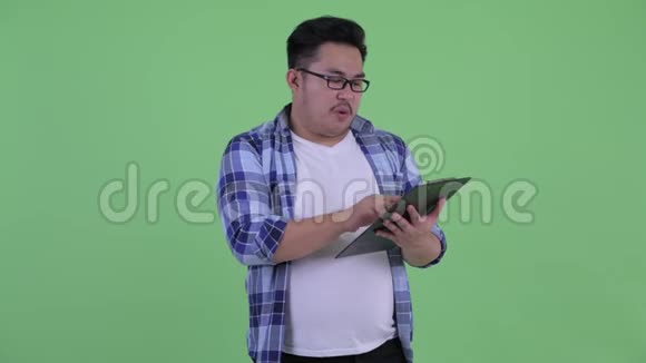 快乐年轻体重超重的亚洲时髦男人一边说一边拿着夹子视频的预览图