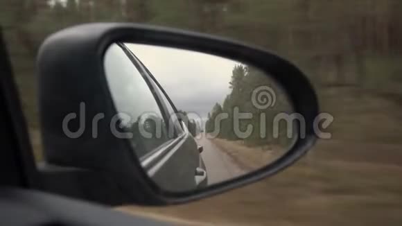 阴天后路上车镜后景穿过松林景观视频的预览图