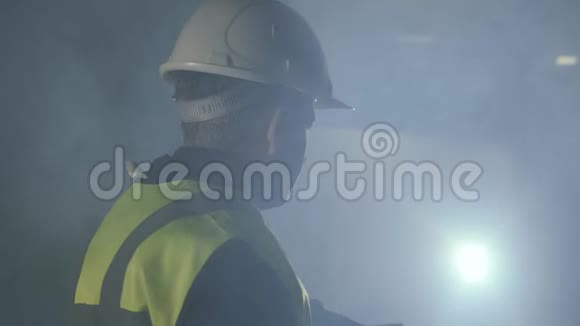 穿着建筑制服和头盔的严肃男子站在黑色背景前聚光灯注视着前方视频的预览图