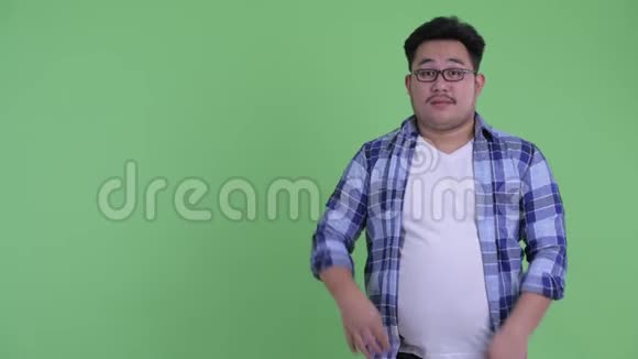 快乐年轻体重超重的亚洲时髦男人展示一些东西竖起大拇指视频的预览图