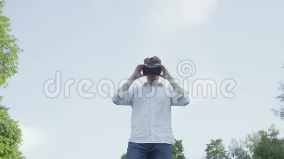 虚拟现实耳机里的年轻人张开双臂模仿公园里飞机的飞行视频的预览图