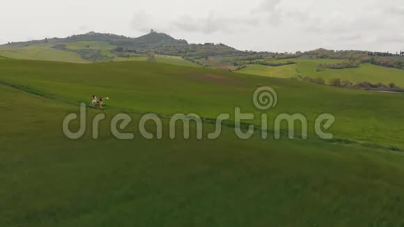 两个年轻的女人在绿色的田野上沿着小路奔跑意大利托斯卡纳视频的预览图