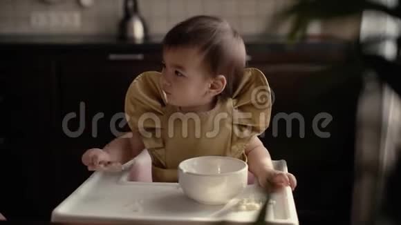 小女孩坐在高椅子后面敲桌子上的勺子视频的预览图