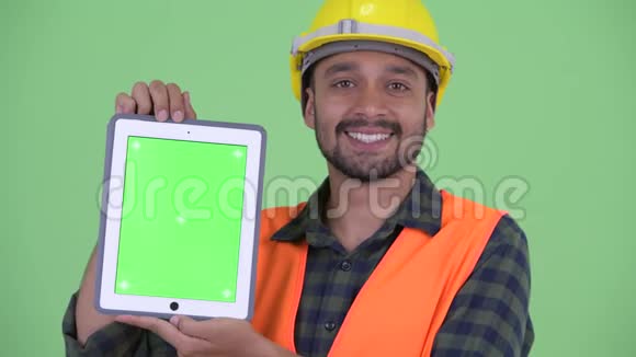 一位年轻的留胡子的波斯人建筑工人展示数字平板电脑视频的预览图