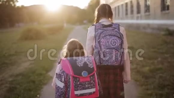 两个姐妹的女学生从学校步行回家姐姐带着妹妹放学回家观点视频的预览图
