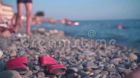一个红色凉鞋的特写在岩石海滩海岸的背景下休息的人海洋视频的预览图