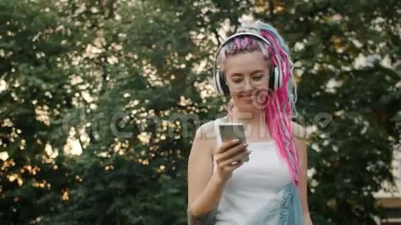 带着耳机的智能手机在户外跳舞的年轻女士视频的预览图