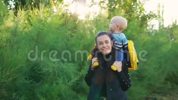 日落时分妈妈带着她的孩子在公园里穿着一件黄色的夹克他们开心地笑着视频的预览图