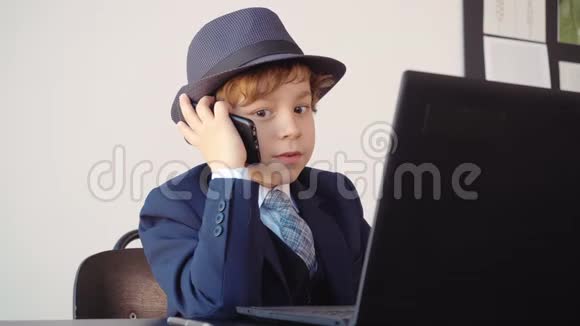 穿西装戴帽子的小男孩老板在他的办公室里说手机成人生活戏仿视频的预览图