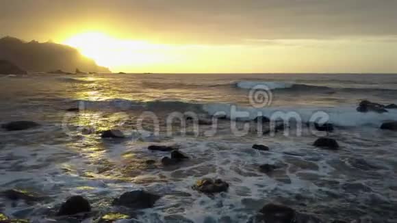 空中观景飞越海浪冲击岩石在美丽的日落光线下喷洒在贝尼霍海滩附近视频的预览图