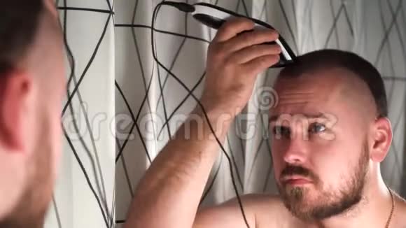 浴室里英俊的男人用电动剃须刀剃头视频的预览图