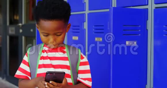 非洲裔美国小学生在学校走廊上用手机带书包的正面景色视频的预览图