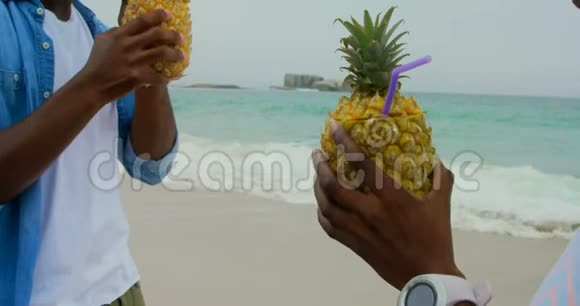 非裔美国人夫妇在海滩上品尝菠萝果汁视频的预览图
