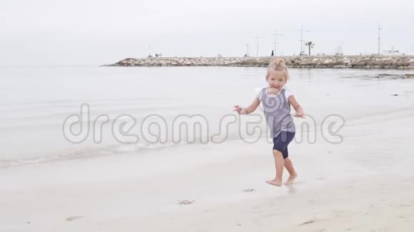 美丽的小女孩沿着海滨奔跑视频的预览图
