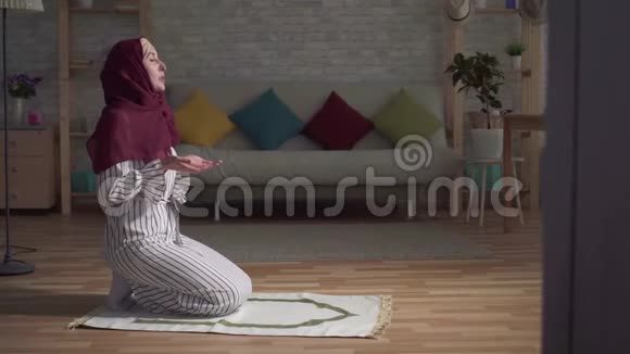 穿着传统围巾在客厅地毯上祈祷的穆斯林妇女视频的预览图