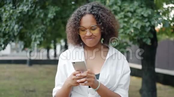 在公园户外与智能手机交流的非裔美国妇女视频的预览图