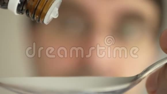 药物病毒保护滴在勺子与模糊的脸吞咽和弯曲超级宏观特写视频的预览图