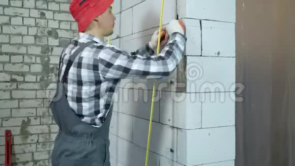 建筑工人在加气混凝土砌块墙上安装夹子的倾斜向上拍视频的预览图