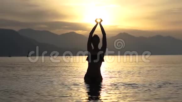 女人在海上时用双手在头顶上做了一颗心动作缓慢视频的预览图