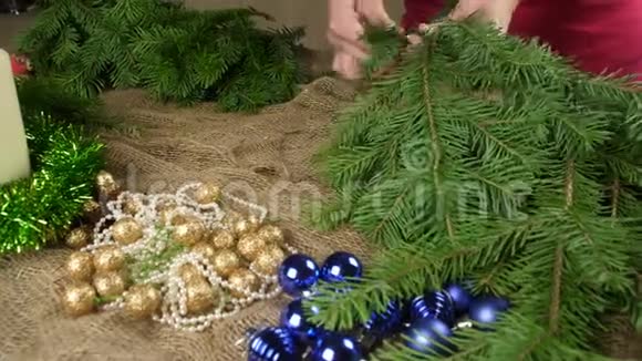 花商在闪亮的圣诞玩具背景下为新年作文准备冷杉树枝创造圣诞节视频的预览图