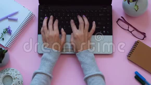 女士双手在笔记本电脑上工作背景为现代粉色工作空间从上面看视频的预览图