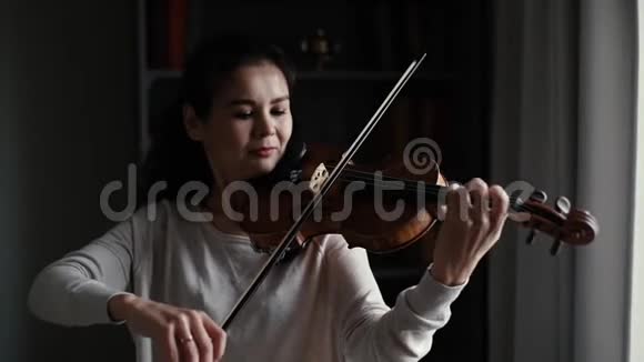 可爱的年轻女子慢动作拉小提琴视频的预览图