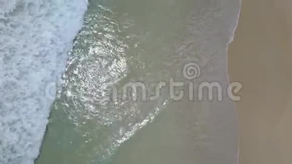 海浪冲刷海滩海岸的垂直镜头用白色的沙滩无人机4K拍摄视频的预览图
