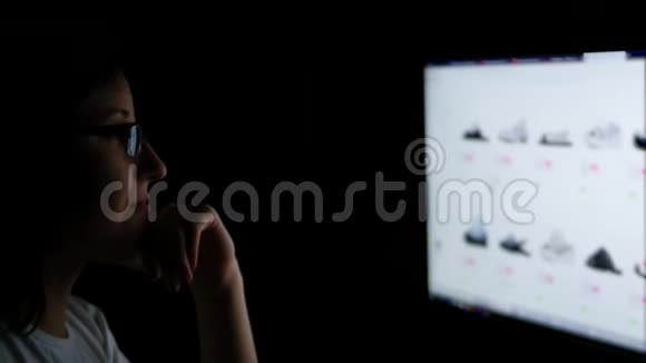 晚上一个戴着眼镜的黑发女人在家玩电脑在网上浏览鞋子视频的预览图