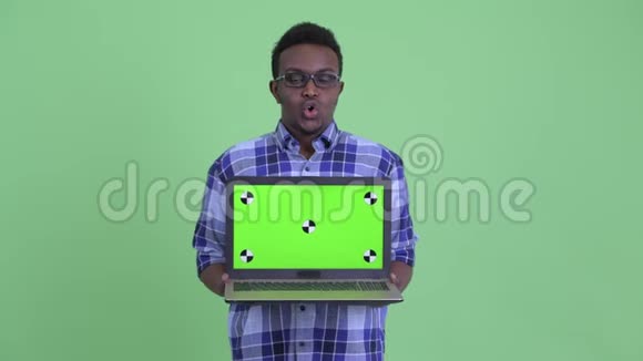 快乐的年轻非洲时髦男人一边说话一边拿笔记本电脑视频的预览图
