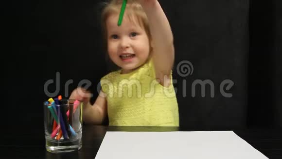 小女孩用绿色铅笔在纸上画画视频的预览图