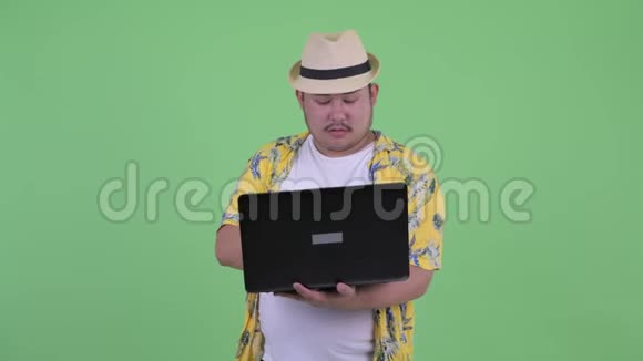 快乐年轻的超重亚洲游客思考笔记本电脑视频的预览图