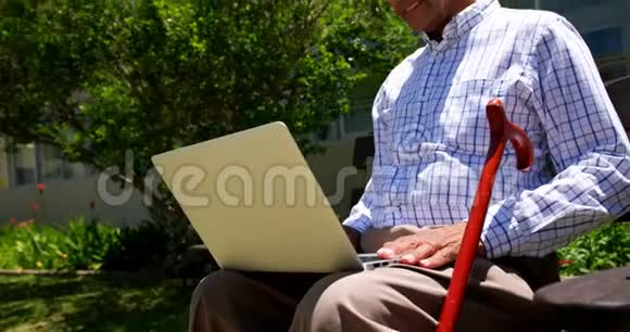 活跃的亚洲老人在养老院花园使用笔记本电脑的正面景色视频的预览图
