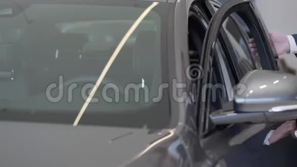 一个穿西装戴眼镜的自信胡子男打开了司机车门坐在车里看着后视镜视频的预览图