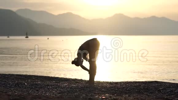 穿着泳衣的女人在日出时在海边慢动作伸展身体视频的预览图