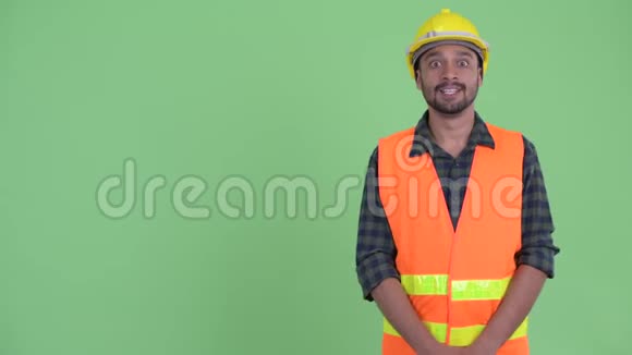 快乐的年轻留胡子的波斯人建筑工人向后面展示视频的预览图