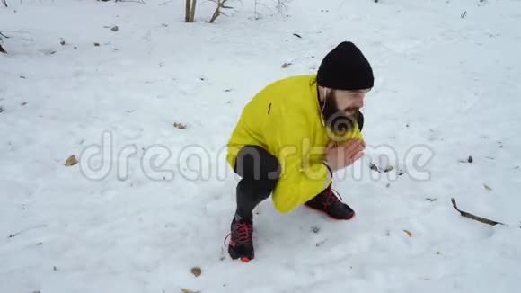 男子运动员在冬季森林中跑步前热身的低镜头视频的预览图