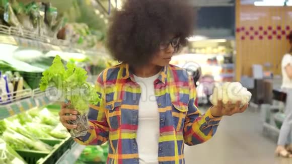 美丽的非裔美国女人发型很难在超市里挑选蔬菜视频的预览图